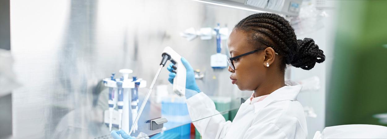 Mulher de bata branca manuseando utensílios de laboratório de biotecnologia