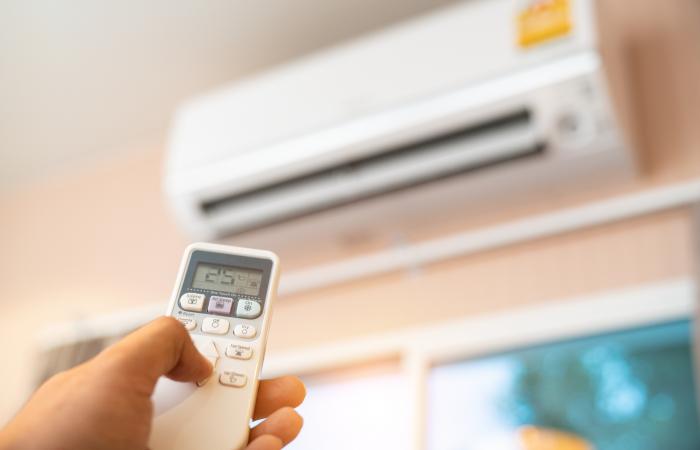 mão de homem a manusear um comendo de ar condicionado