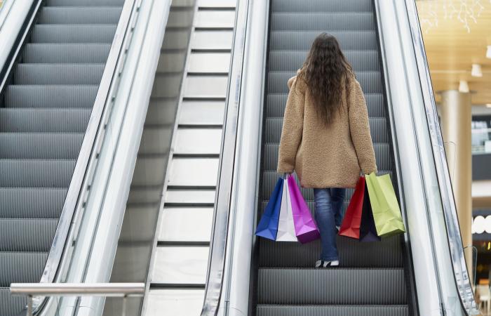 mulher com sacos de compras em escada rolante